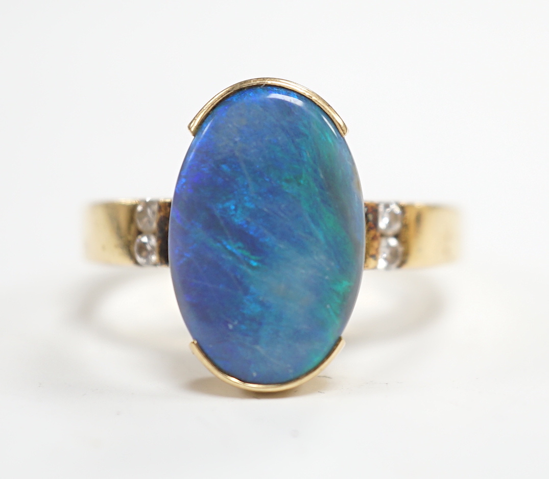 A yellow metal and black opal oval dress ring, with diamond chip shoulders, size P, gross weight 5.7 grams.